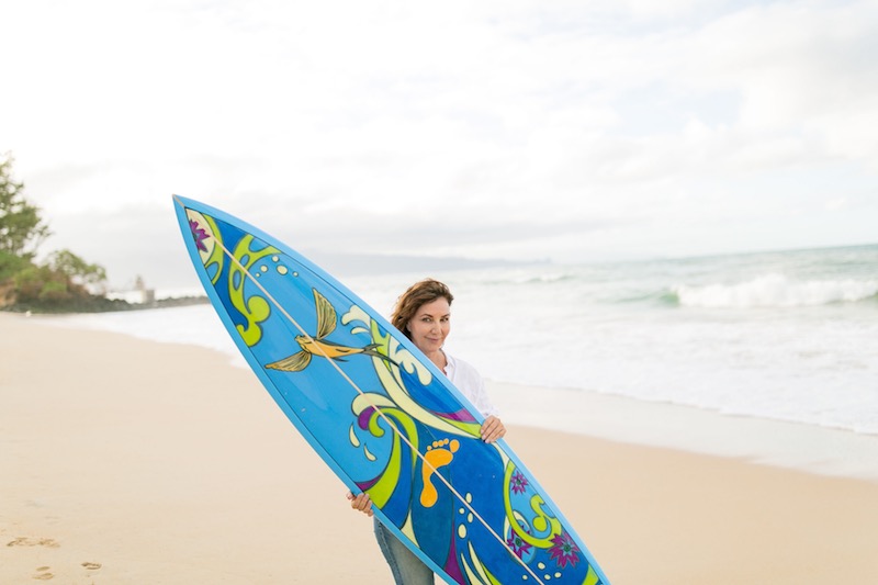 Kim McDonald poses with a custom surfboard that she painted. The auction for the board will benefit the Paia Youth and Cultural Center