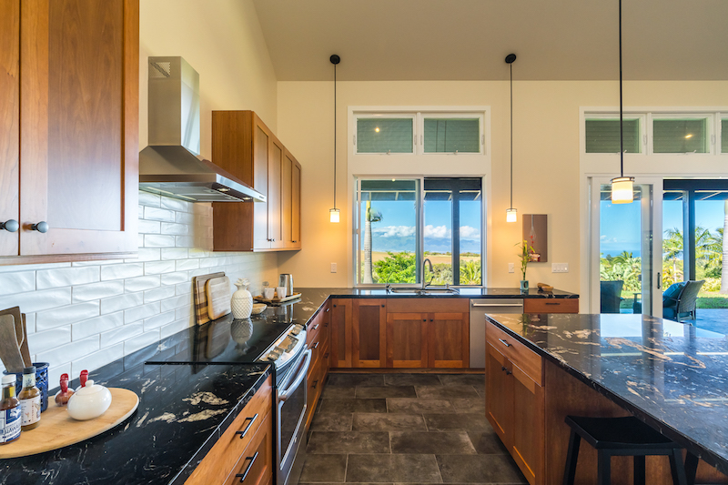 Black granite counters, natural stain cherry wood cabinets, stainless appliances, an oversized island with ohia wood support posts