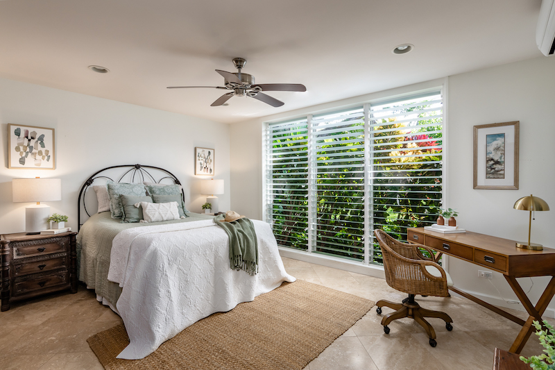 A floor to ceiling jalousie window opens up to show views of the tropical landscaping